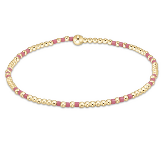Gold and pink beaded bracelet on a white background