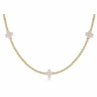 Gold necklace with small cross pendants on a white background enewton