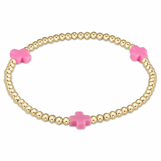Gold beaded bracelet with pink cross-shaped beads on a white background enewton