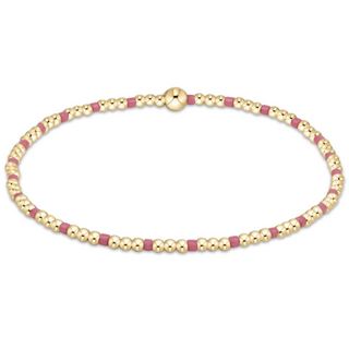 Gold and pink beaded bracelet on a white background