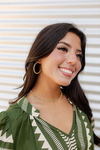 Woman wearing a green patterned dress with a neutral background by enewton