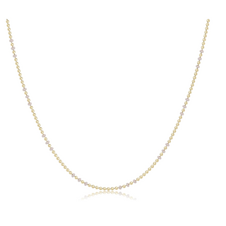 Gold necklace with small beads on a white background by e newton