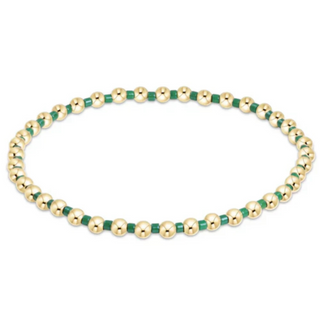 Gold and green beaded bracelet on a white background by e newton