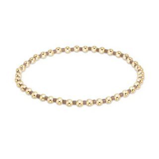 Gold beaded necklace on a white background by e newton