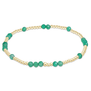 Bracelet with green beads and gold accents on a white background by e newton