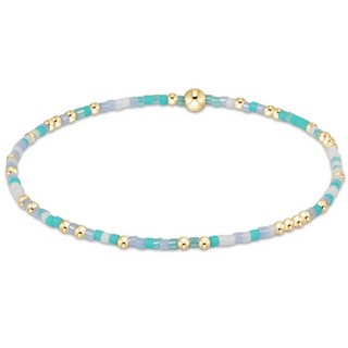 Beaded bracelet with turquoise and gold beads on a white background