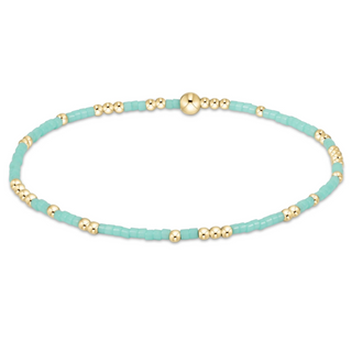Turquoise beaded bracelet with gold beads on a white background