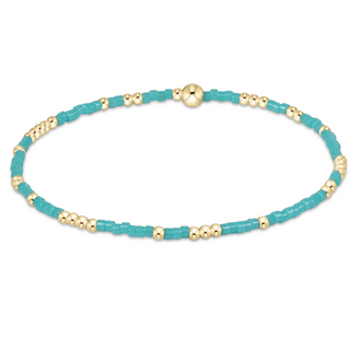 Turquoise beaded bracelet with gold accents on a white background
